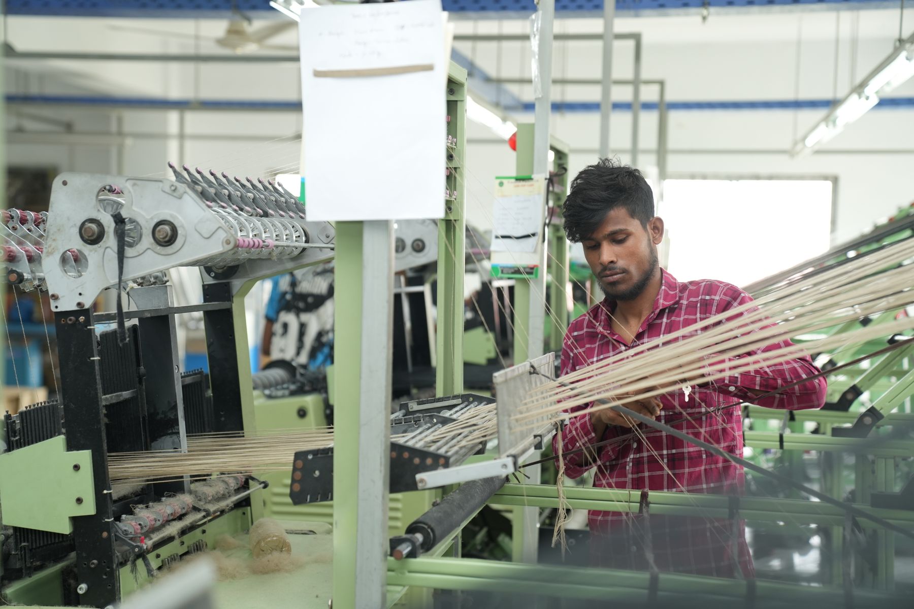 Textile technician working with yarn on industrial fabric machinery